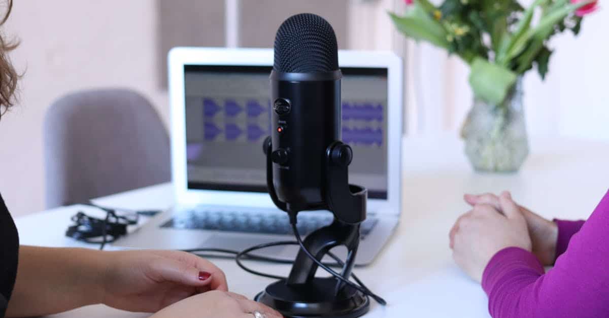Two women recording a podcast in a modern office with a microphone and laptop.